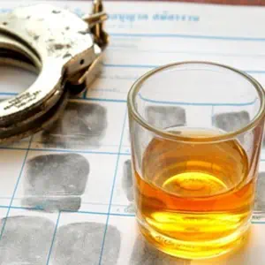 Alcohol and handcuffs placed on a table, depicting a scene that may involve law enforcement