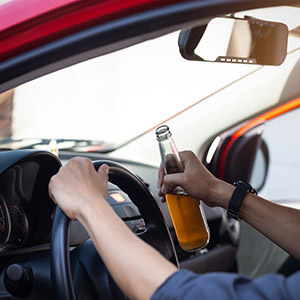 Driver holding an open beer bottle, illustrating a First-Time DWI Arrest and defense in Rockland County law