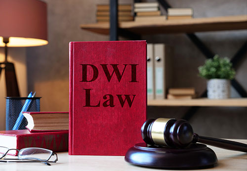 Red law book labeled DWI Law beside judge’s gavel on a desk in an office setting.