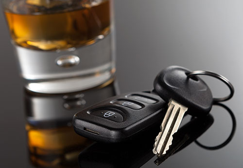 Gavel, car key, and alcohol glasses symbolizing DWI charges and legal defense.